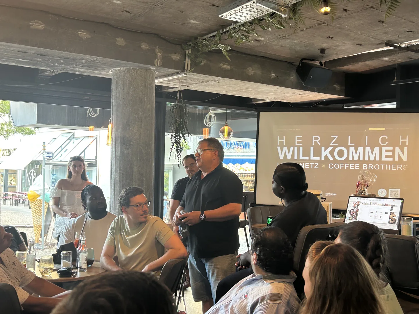 Ein Teilnehmer stellt sich vor der Willkommensfolie den übrigen Gästen vor